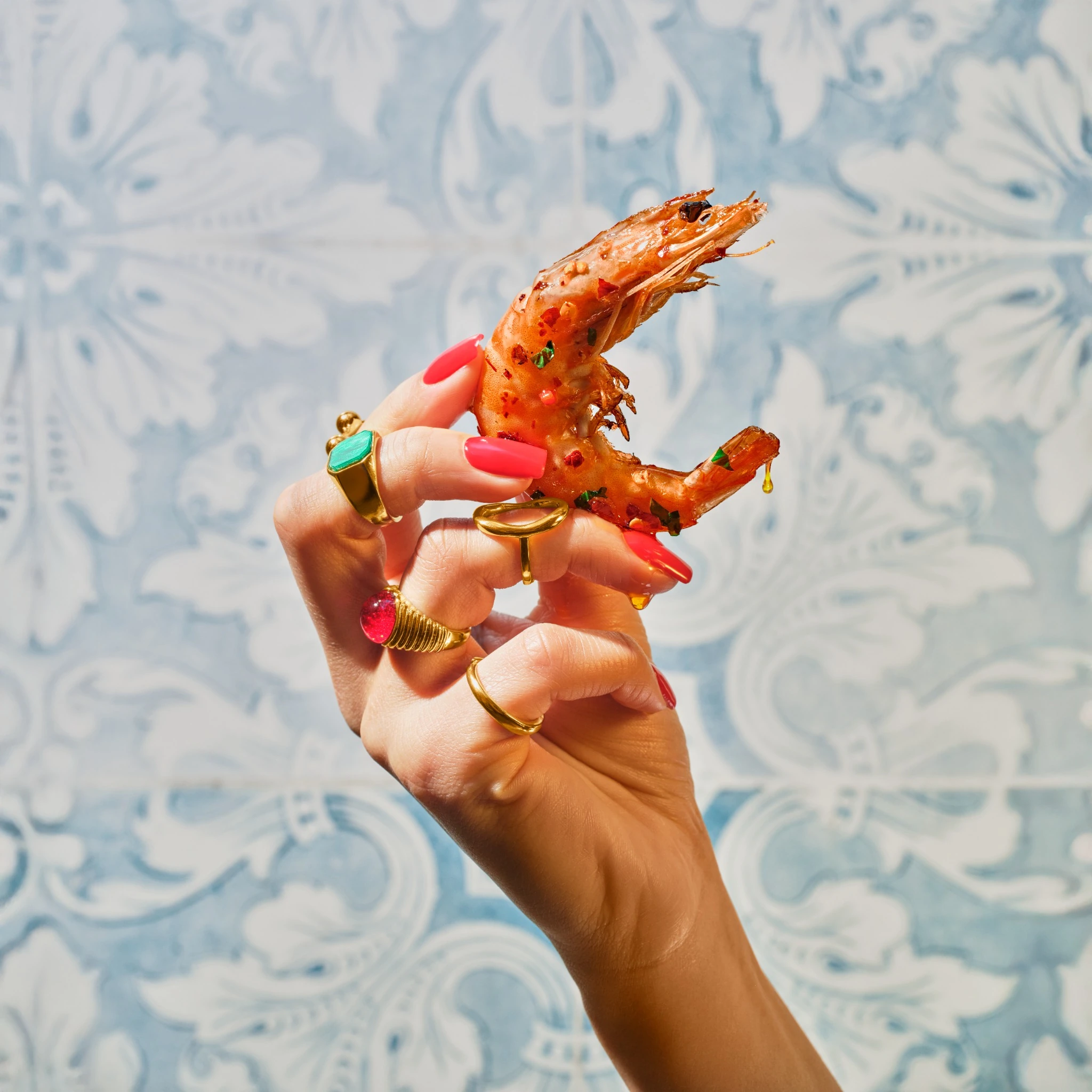 Glazed prawn held in a jewelled hand